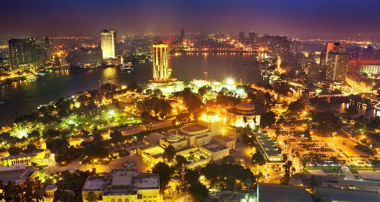 Le paysage urbain illuminé du Caire et ses ponts se reflétant sur le Nil la nuit.