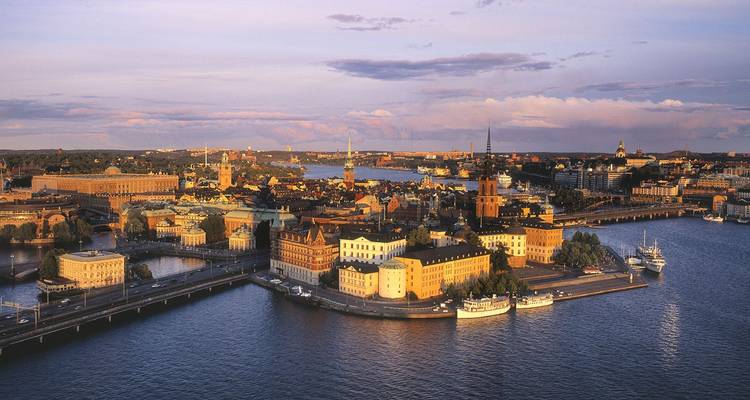 Panorama aéreo del centro histórico de Estocolmo rodeado de agua brillante bajo la cálida luz del atardecer.