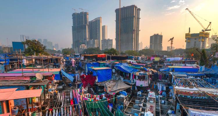 Colorful open-air Dhobi Ghat laundry with towering modern skyscrapers rising behind in Mumbai.