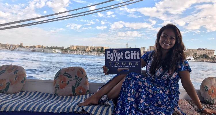 Vrouw die op een boot zit en een Egypt Gift Tours bord vasthoudt.