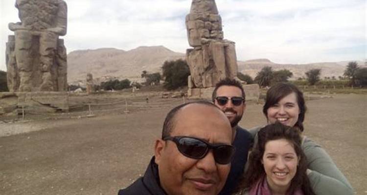 Los turistas se toman una selfie con las enormes estatuas de los Colosos de Memnón elevándose detrás de ellos.