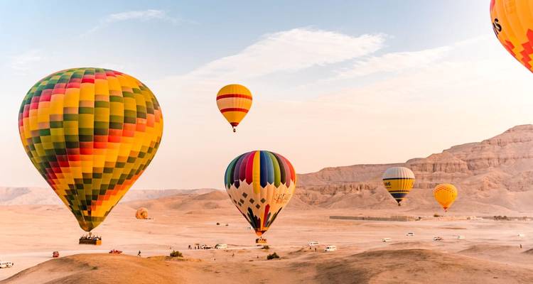 Los globos aerostáticos de colores vivos flotan sobre los acantilados del desierto al amanecer cerca de Luxor.