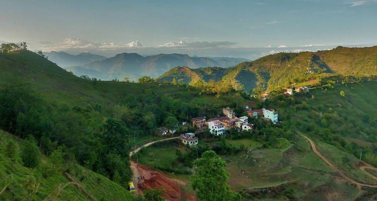 Village in hilly terrain with mountains in the distance.