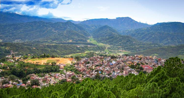 Overview of a town nestled within mountain ranges and greenery.