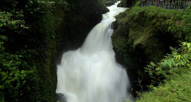 Waterfall flowing between lush green cliffs.
