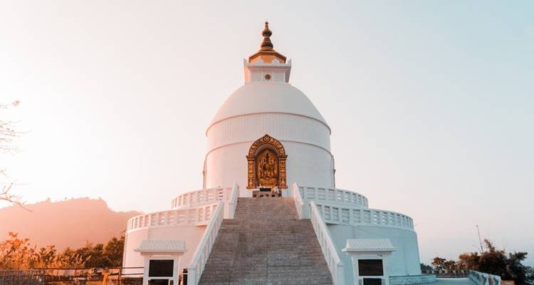 Eine große Stupa mit Treppen und Inschriften, die im Sonnenlicht erstrahlt.