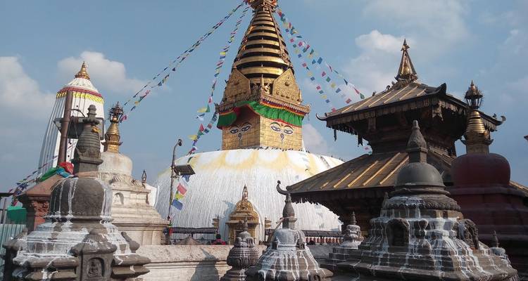 Swayambhunath Stupa mit Gebetsfahnen und kunstvollen Details unter blauem Himmel.