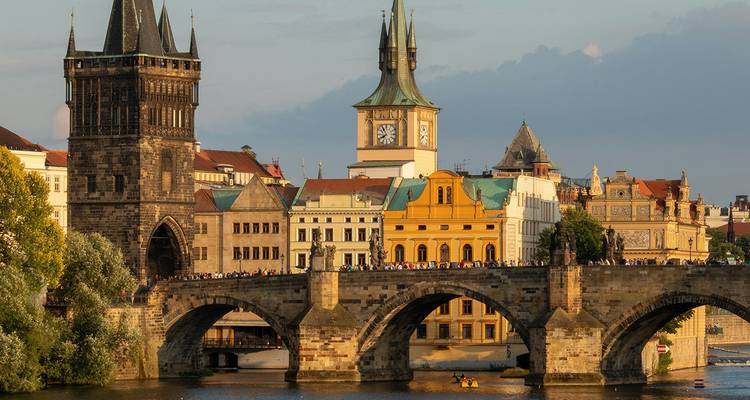 Gouden avondlicht verlicht de Karelsbrug en de torens van de Oude Stad die zich uitstrekken over de rivier de Moldau in Praag.