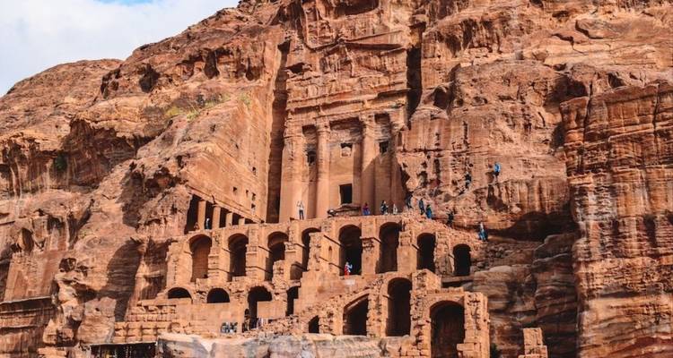 Ancient rock carvings in Petra with visitors.