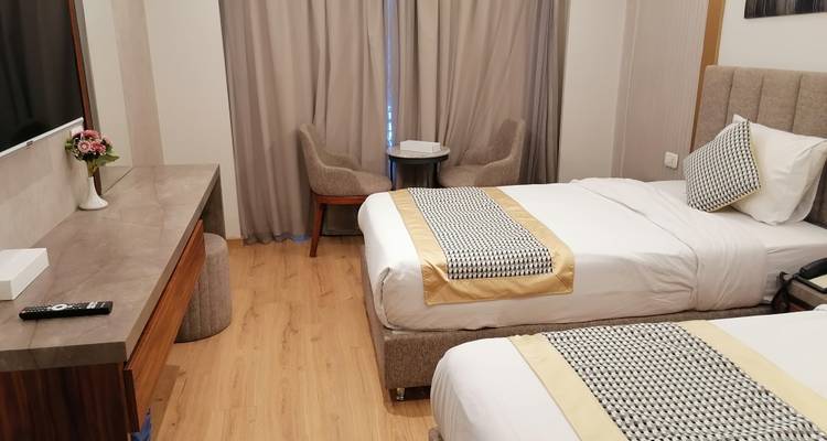 Hotelzimmer mit zwei Einzelbetten, einem kleinen Tisch und Stühlen.