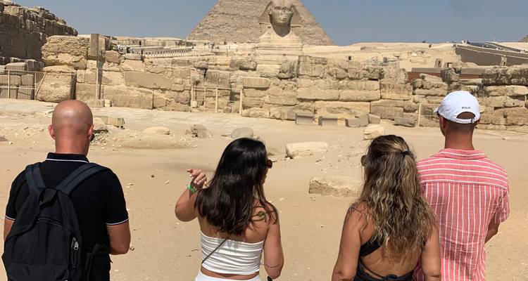 Travelers from behind pointing toward the Sphinx against the desert ruins.