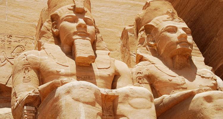 Nahaufnahme von zwei riesigen Statuen, die in Fels gemeißelt sind.