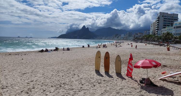 Strand mit Surfbrettern und Stadtskyline in der Ferne.