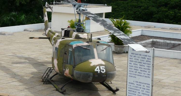 Military helicopter displayed on the rooftop of Independence Palace with explanatory plaque.