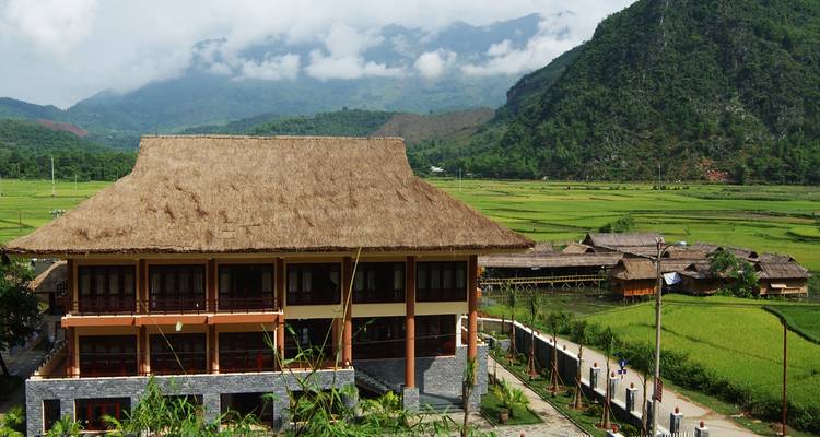 Pueblo en un valle con arrozales y montañas.
