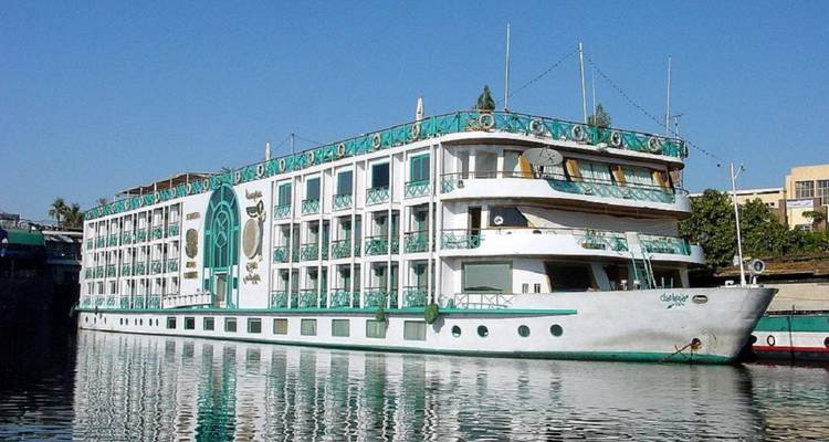 White multi-deck Nile cruise ship reflected on calm water under clear blue sky