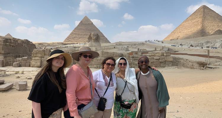 Friends smiling with the Sphinx and two pyramids forming an iconic Giza backdrop.