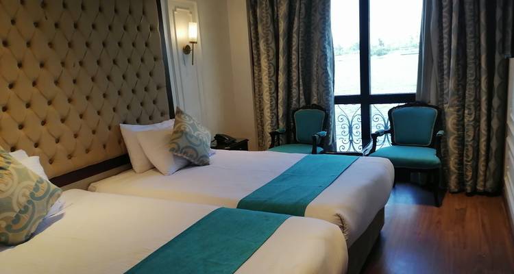 Zimmer mit zwei Einzelbetten, eleganter Einrichtung und Flussblick.