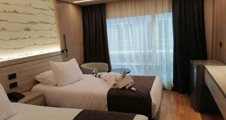 Une chambre d'hôtel soignée avec deux lits et une vue par la fenêtre.