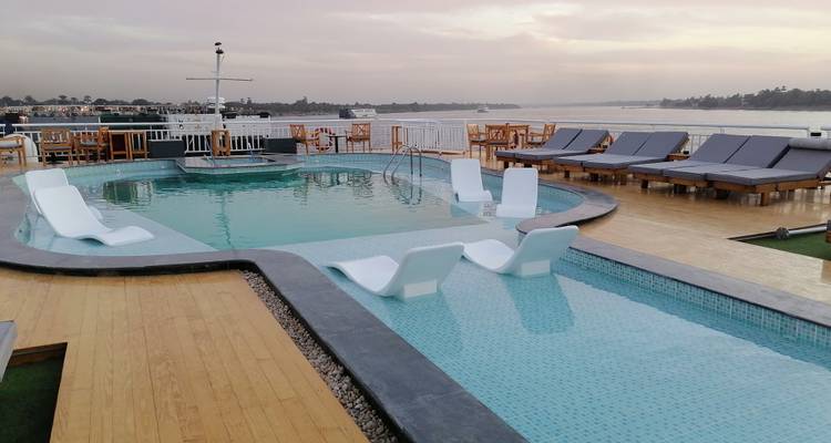 Une piscine de pont ensoleillée sur un navire de croisière avec des chaises longues tout autour.