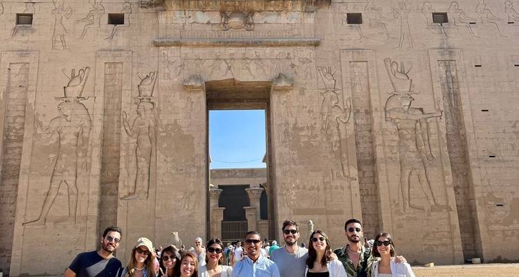 Eine Gruppe von Touristen vor einem großen Eingang mit antiken Schnitzereien.