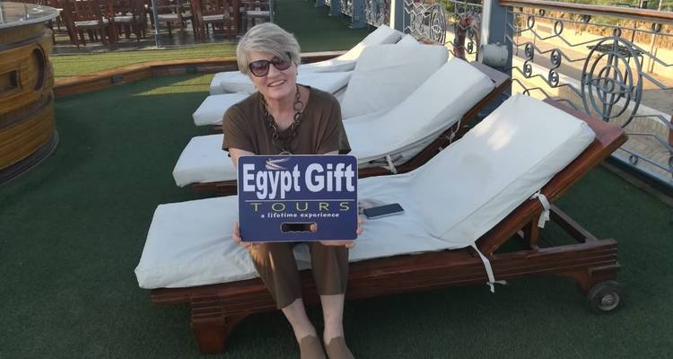 Ein Tourist, der ein Touristenschild hält, während er auf Liegestühlen sitzt.