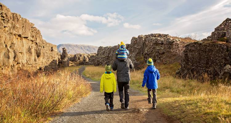 Family walking along a rocky path with mountain view.
