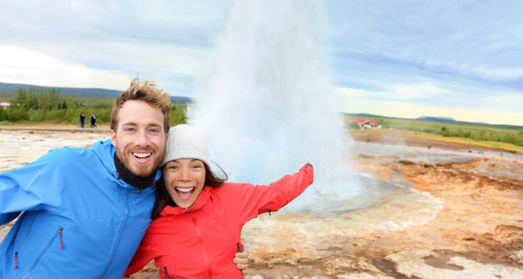 Couple posing in front of a geyser explosion.