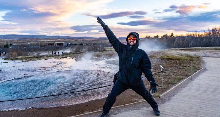 Person posing energetically in front of a steaming geothermal area.