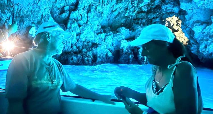 Deux personnes dans une grotte éclairée en bleu lors d'une visite en bateau.
