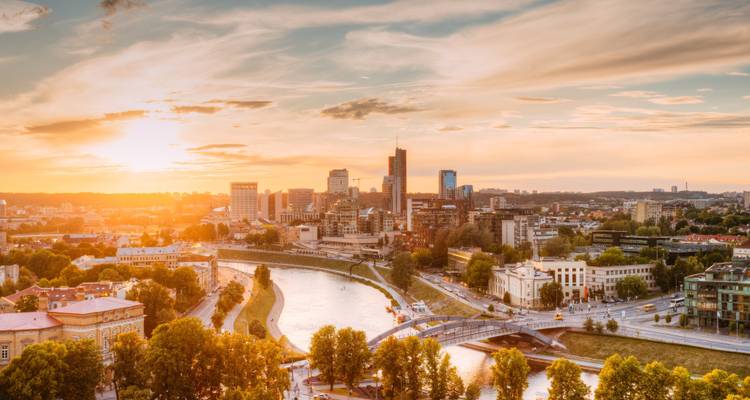 Aerial view of a city with a river and modern buildings at sunset.