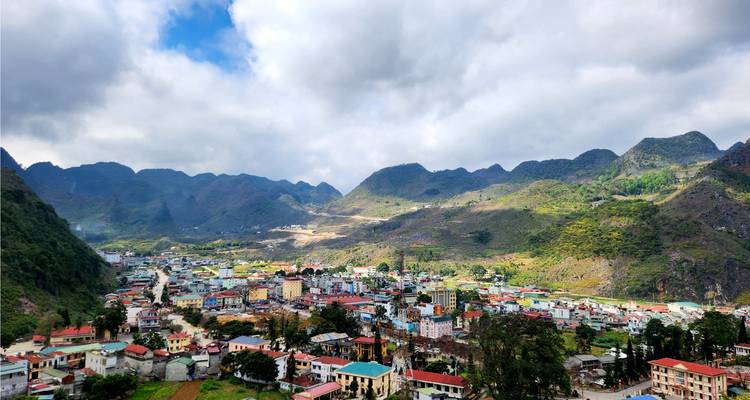 Un pueblo situado en un valle rodeado por terreno montañoso bajo un cielo nublado.