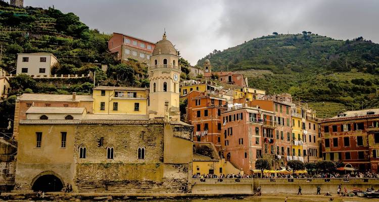 Colorful buildings of a coastal village against a hillside.