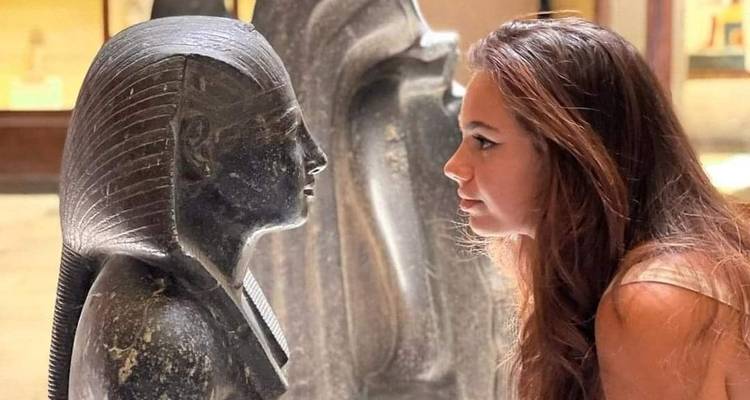 Vrouw die interacteert met een oud stenen beeld in een museum.