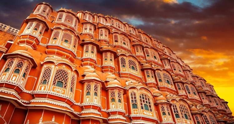 Hawa Mahal gevel in Jaipur tegen een dramatische zonsonderganghemel.