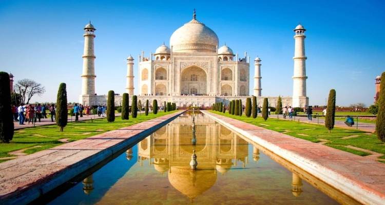 Taj Mahal in Agra met weerspiegeling in het water en toeristen op de voorgrond.