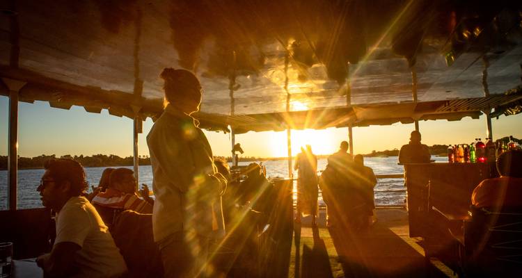 Silhouettes of people on a boat watching a beautiful sunset over the water.