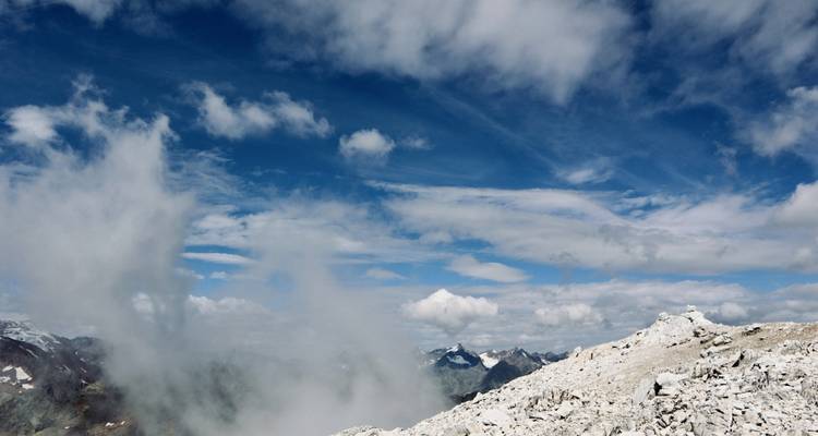 Bergtop onder een heldere blauwe lucht met wolken.