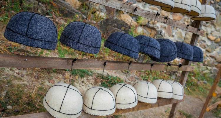 Des rangées de bonnets en laine qui sèchent sur un support en bois dans un cadre rural.