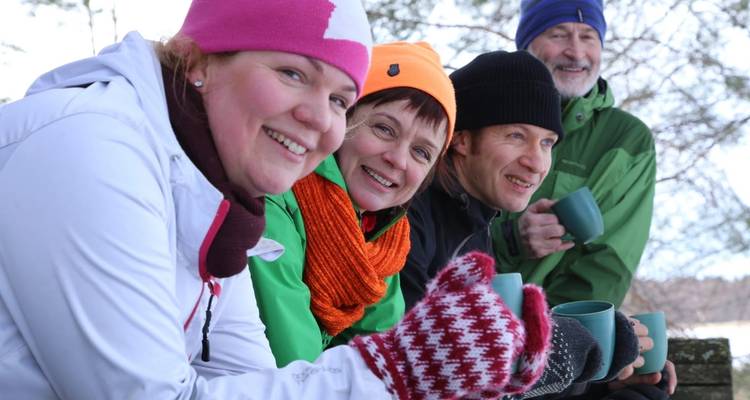 Gruppe von Freunden, die heiße Getränke im Freien genießen.