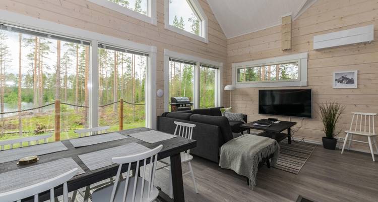 Modernes Hütteninterieur mit großen Fenstern und Waldblick.