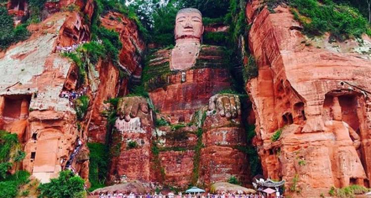 Reusachtige stenen Boeddha uitgehouwen in een rode klif.