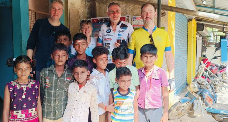 Groep mensen, inclusief kinderen, die poseren voor een foto in een stedelijke omgeving.