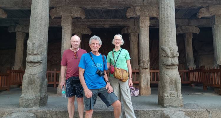 Drie bejaarde toeristen die voor eeuwenoude steengravures staan.