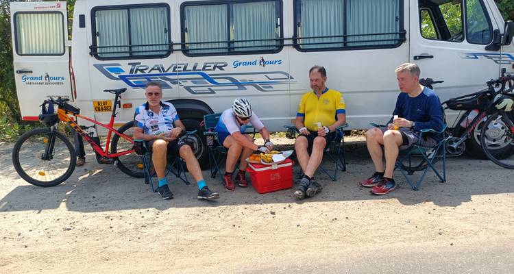 Groep fietsers die een pauze nemen bij een busje met wat snacks.