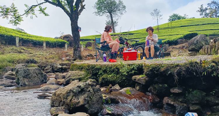 Twee mensen die bij een beek zitten in een aangelegde omgeving.