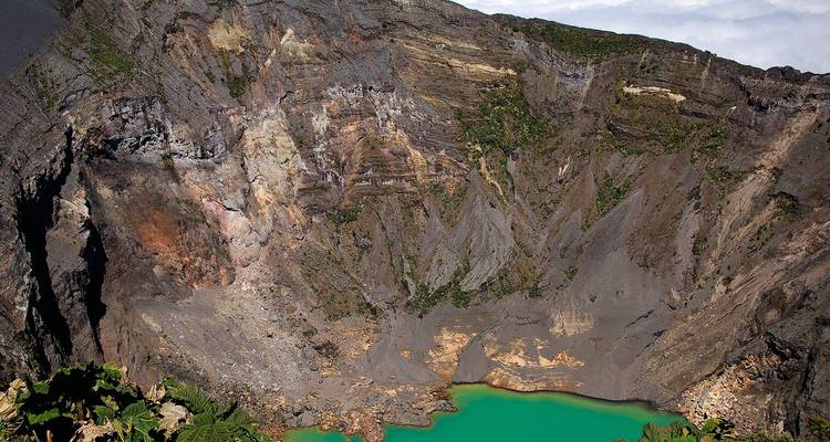 Cratère volcanique abrupt aux parois rocheuses multicolores et à un lac turquoise éclatant au fond