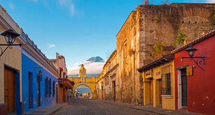 Une rue coloniale colorée encadre l'Arche Santa Catalina avec un volcan s'élevant à l'arrière-plan à Antigua.