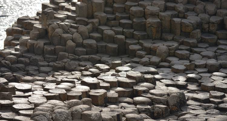 Close-up of weathered hexagonal basalt columns stacked along the shoreline at the Giant’s Causeway