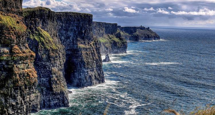 Dramatic sea cliffs plunging into the Atlantic Ocean with waves crashing below at the Cliffs of Moher, Ireland